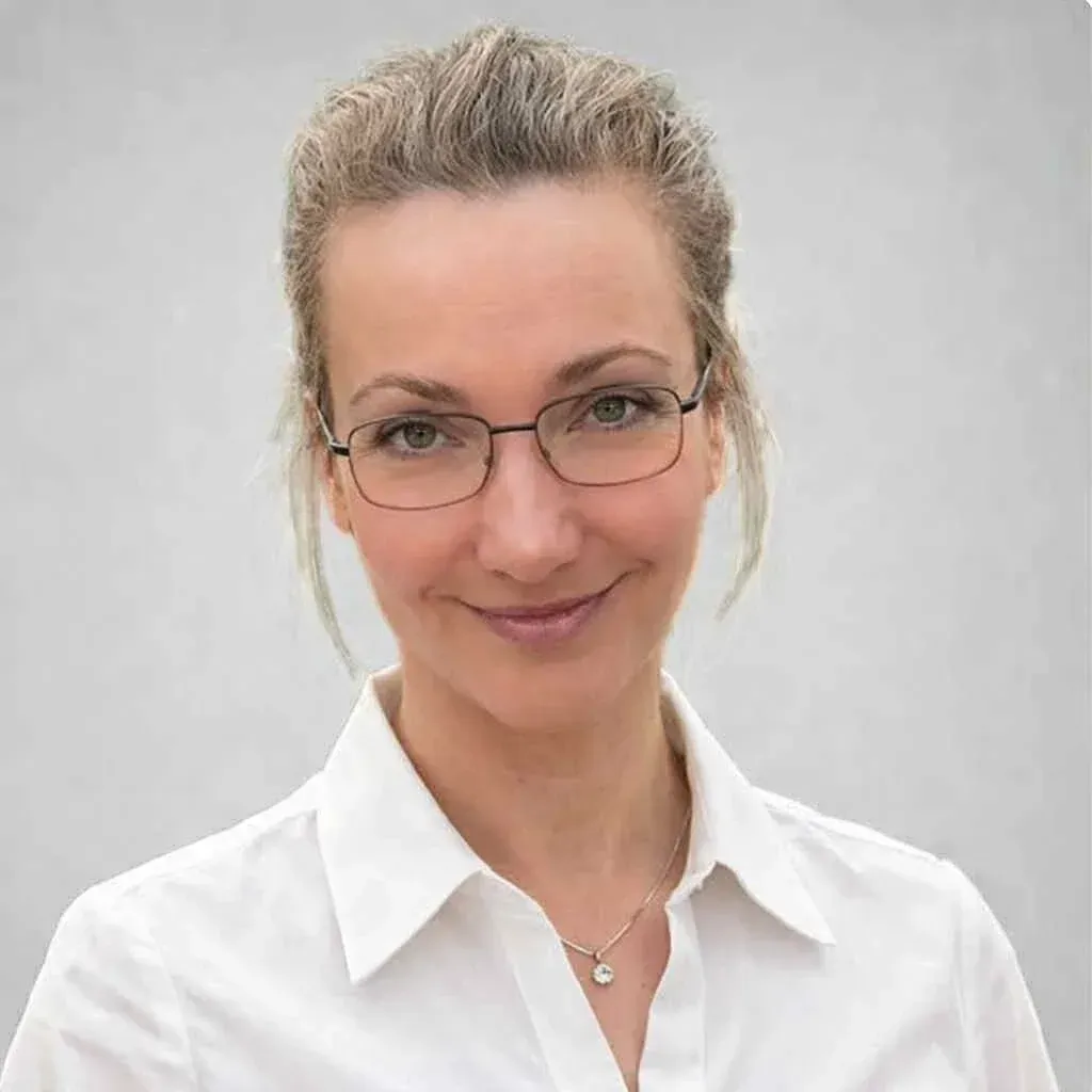 Bendik Grieg Skjold med lys hud og brunt hår iført en hvit polotrendgenser, mot en hvit vegg.