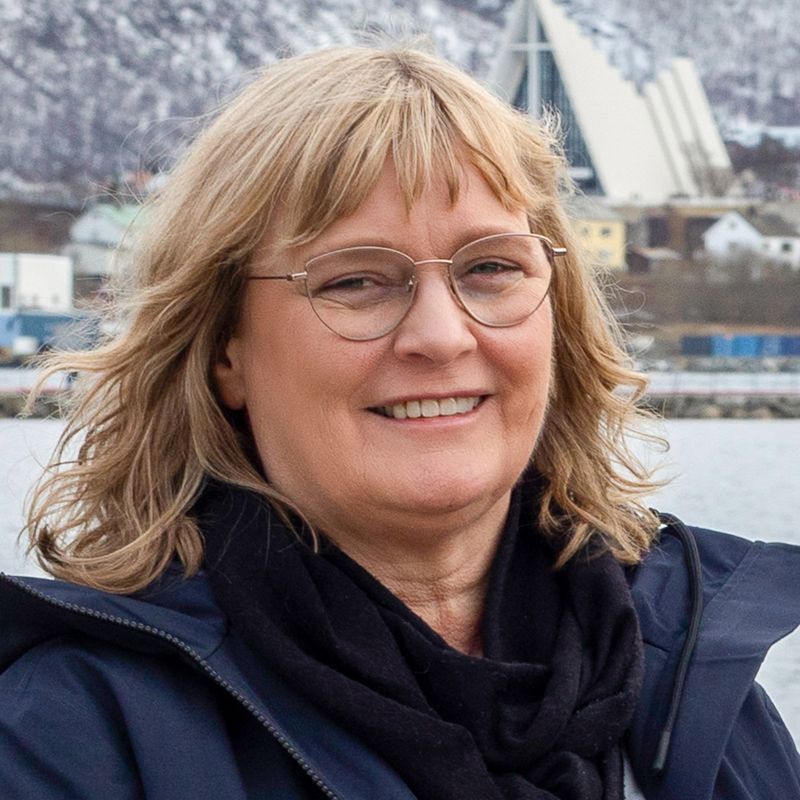 Woman with blonde hair and glasses smiles outdoors in Tromsø, Norway.