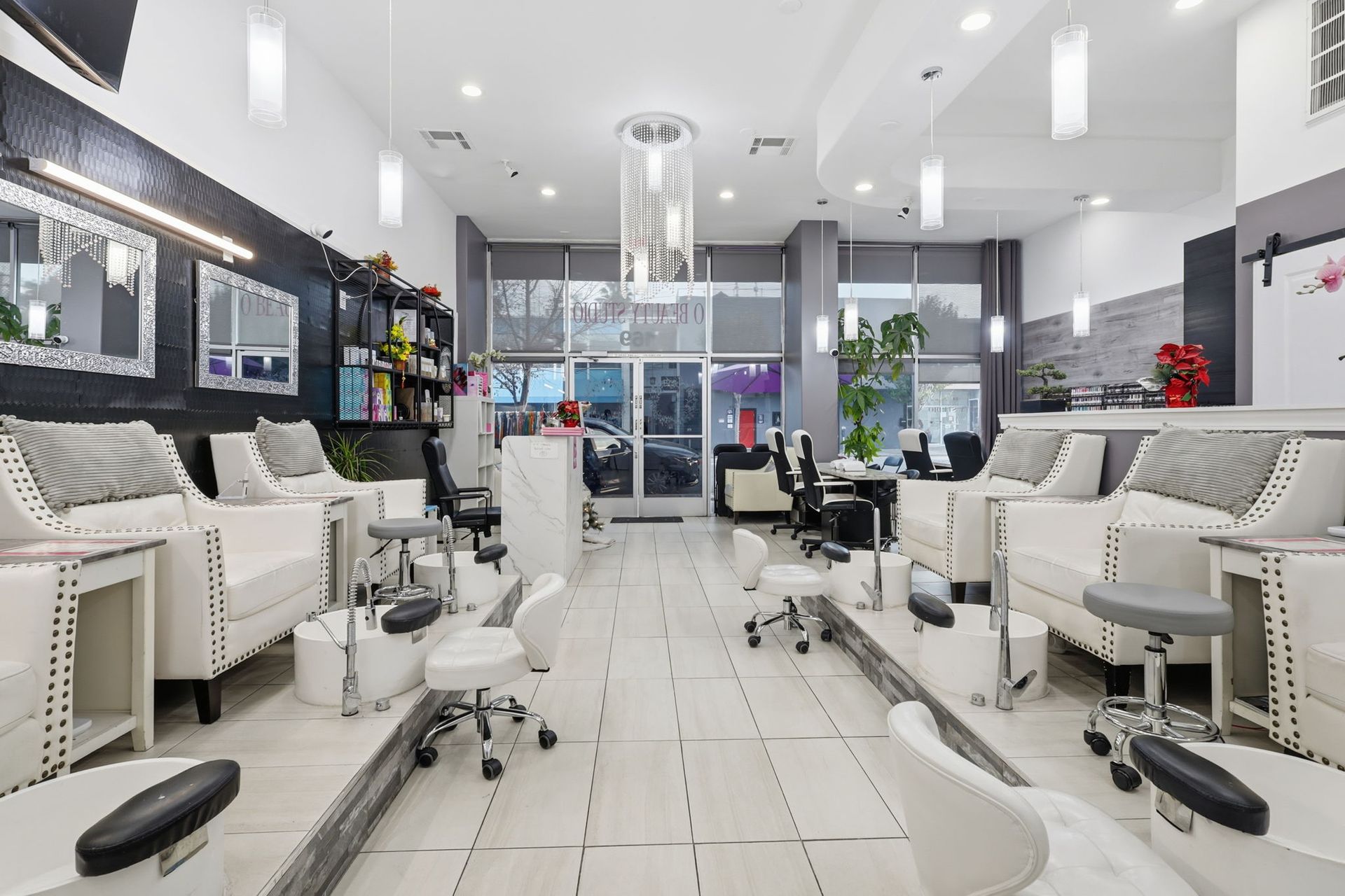A bright, modern nail salon with white chairs, foot baths, and rows of pedicure stations.