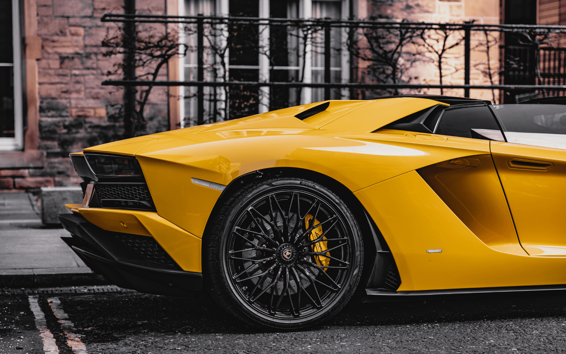 Une lamborghini aventador jaune est garée sur le bord de la route devant un bâtiment.