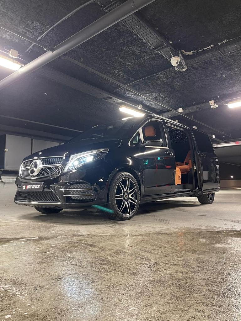 Fourgonnette de luxe noire, porte ouverte, dans un parking souterrain faiblement éclairé.