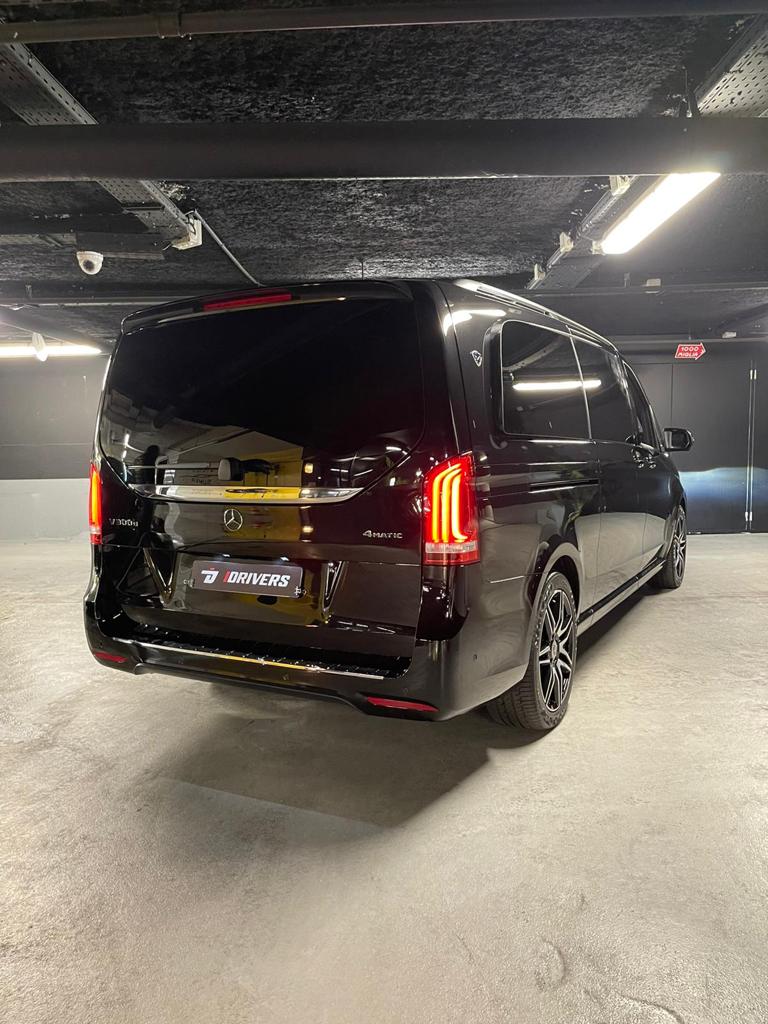 Fourgonnette Mercedes-Benz noire garée dans un garage, éclairée par des plafonniers.