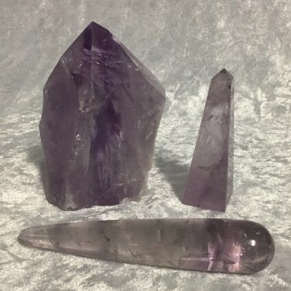 Three Purple Crystals Arranged on A Smooth White Surface — Crystal Cauldron In South Mackay, QLD