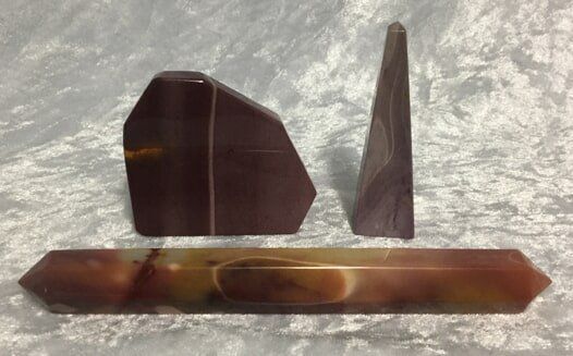 Three Pieces of Brown and Green Stone Arranged on A Wooden Table — Crystal Cauldron In South Mackay, QLD