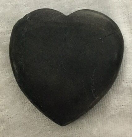 A Black Heart-Shaped Stone Resting on A White Cloth — Crystal Cauldron In South Mackay, QLD