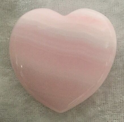 A Pink Heart-Shaped Stone Resting on A White Cloth — Crystal Cauldron In South Mackay, QLD