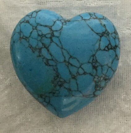 A Turquoise Heart-Shaped Stone Resting on A White Cloth — Crystal Cauldron In South Mackay, QLD