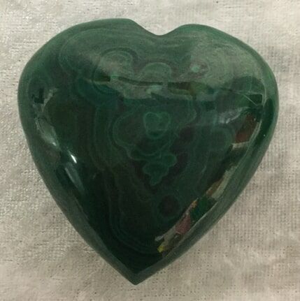 A Green Heart-Shaped Stone Resting on A White Cloth — Crystal Cauldron In South Mackay, QLD
