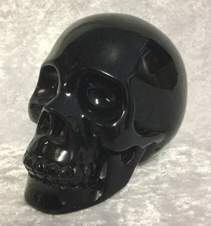 A Black Skull Resting on A Clean White Surface — Crystal Cauldron In South Mackay, QLD