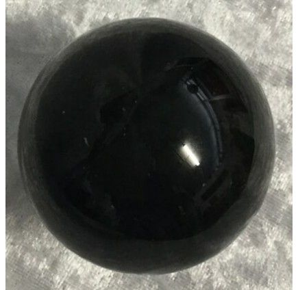 A Shiny, Smooth Black Sphere is Placed on a Textured Gray Surface — Crystal Cauldron In South Mackay, QLD