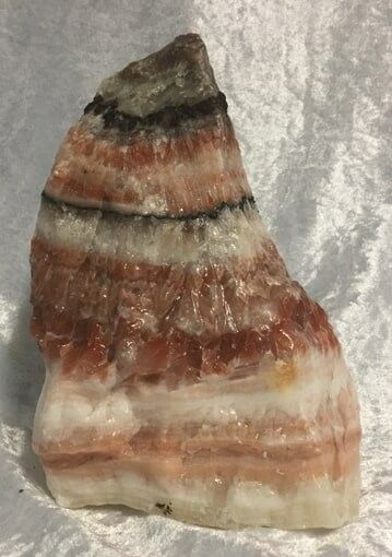 A Large, Textured Rock With Layers of Orange, White, and Black Bands — Crystal Cauldron In South Mackay, QLD
