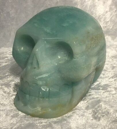 A Light Green Stone Skull Positioned on A White Cloth — Crystal Cauldron In South Mackay, QLD