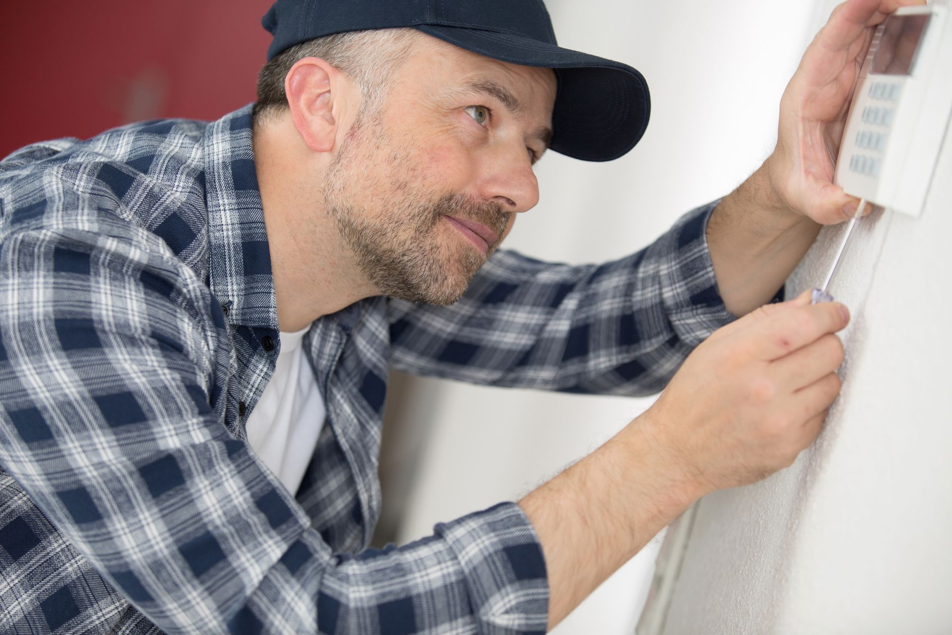 HVAC technician repairing digital heating and cooling thermostat.