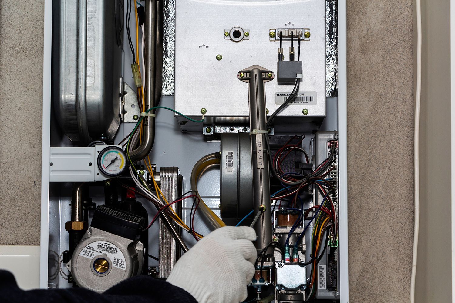 Technician adjusting internal components of a furnace during repair work.