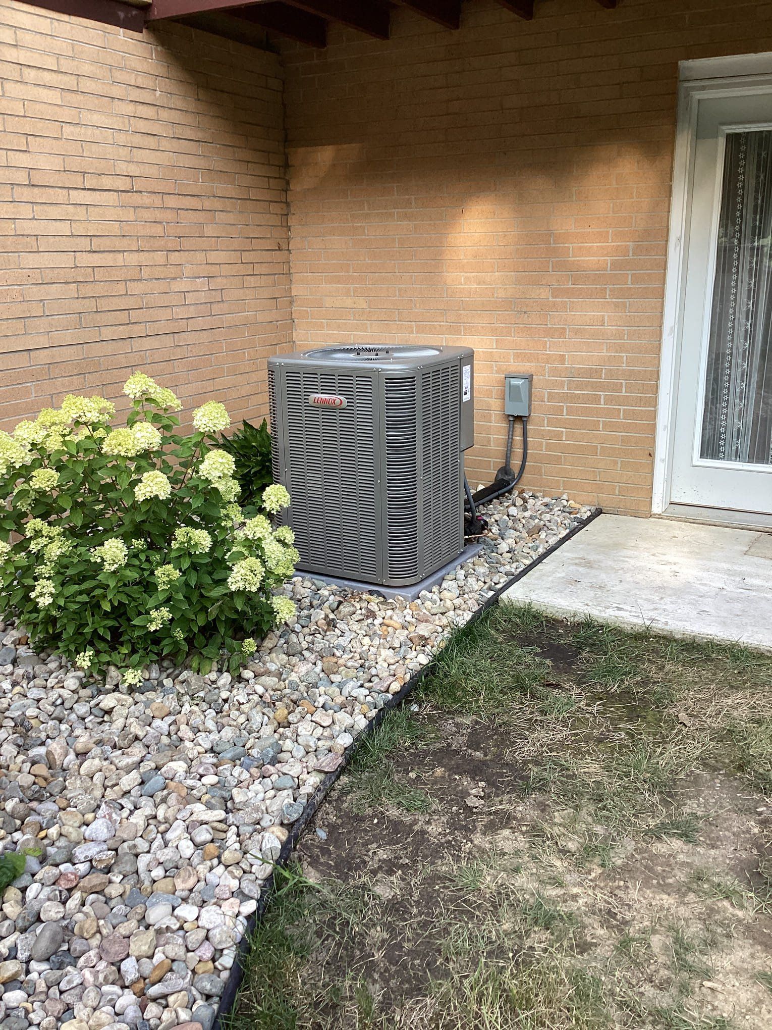 An air conditioner is sitting on the side of a brick building.