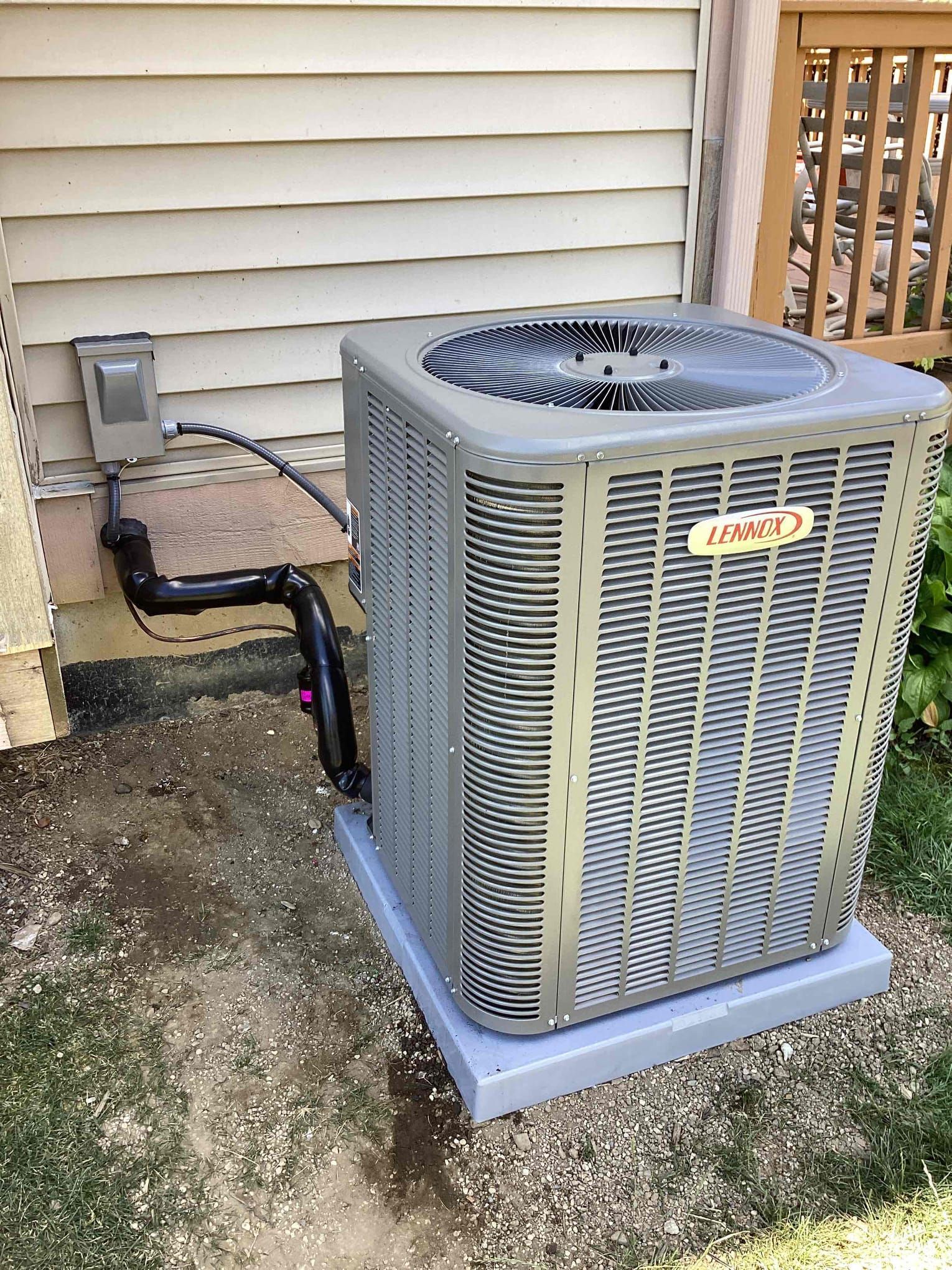A large air conditioner is sitting outside of a house.