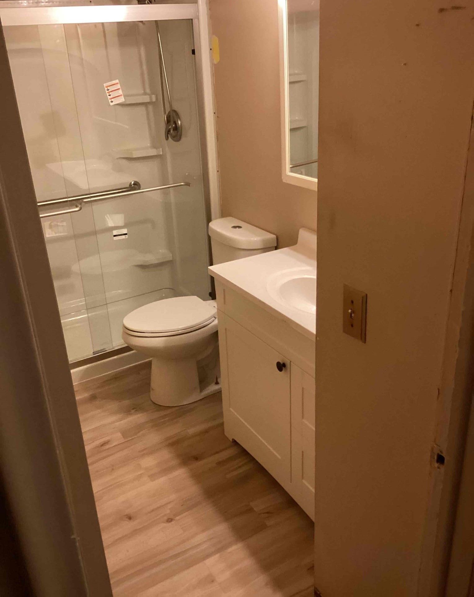 A bathroom with a toilet , sink , shower and mirror.
