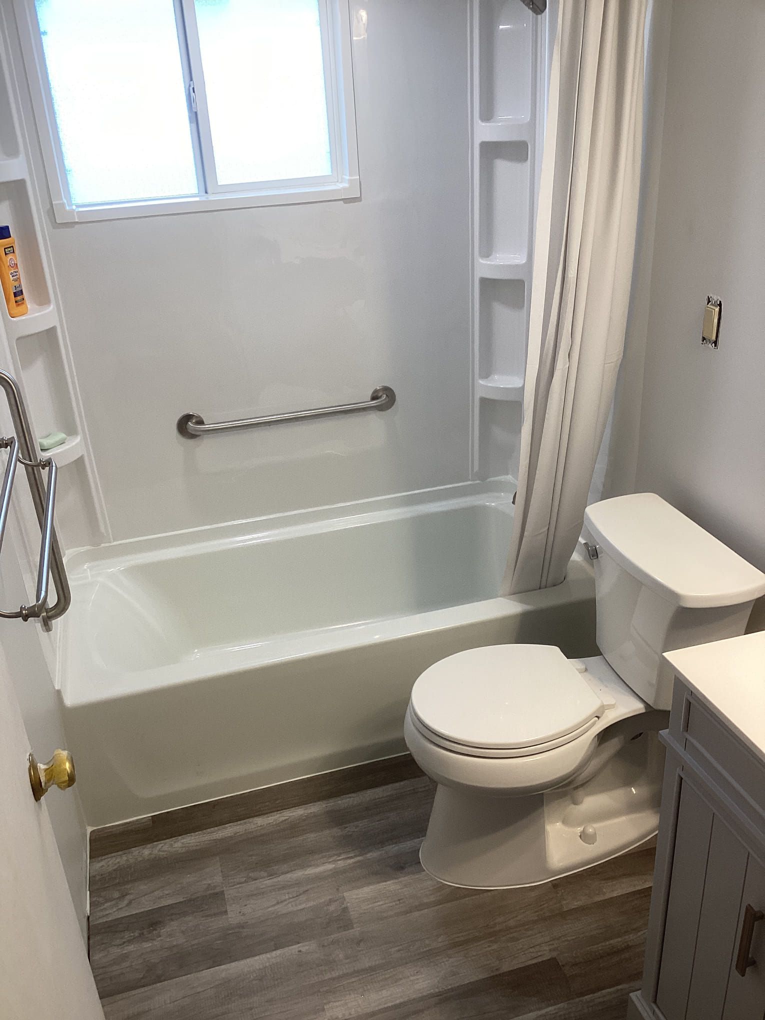 A bathroom with a toilet , bathtub and window.