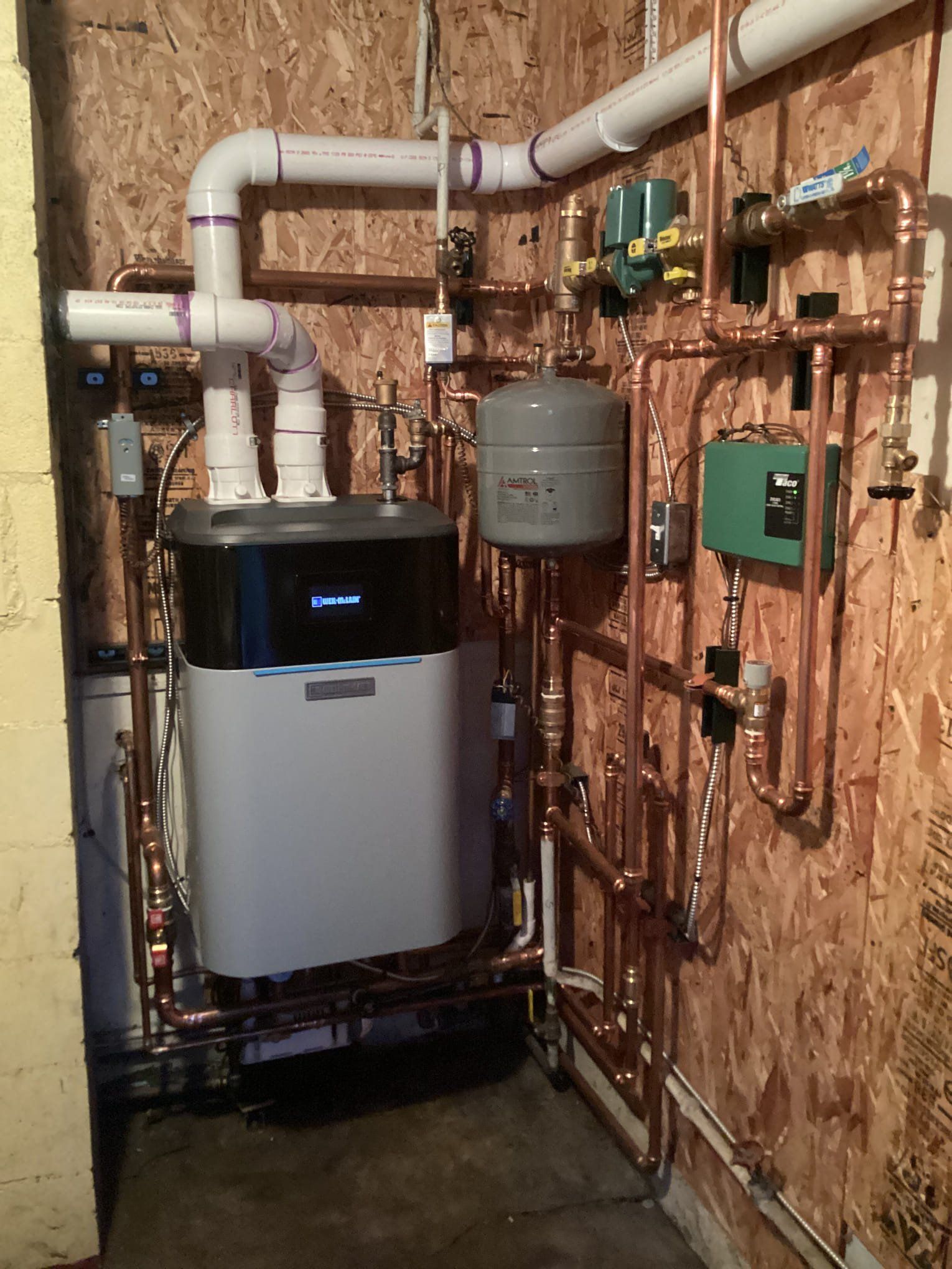 A room with a boiler and pipes on the wall