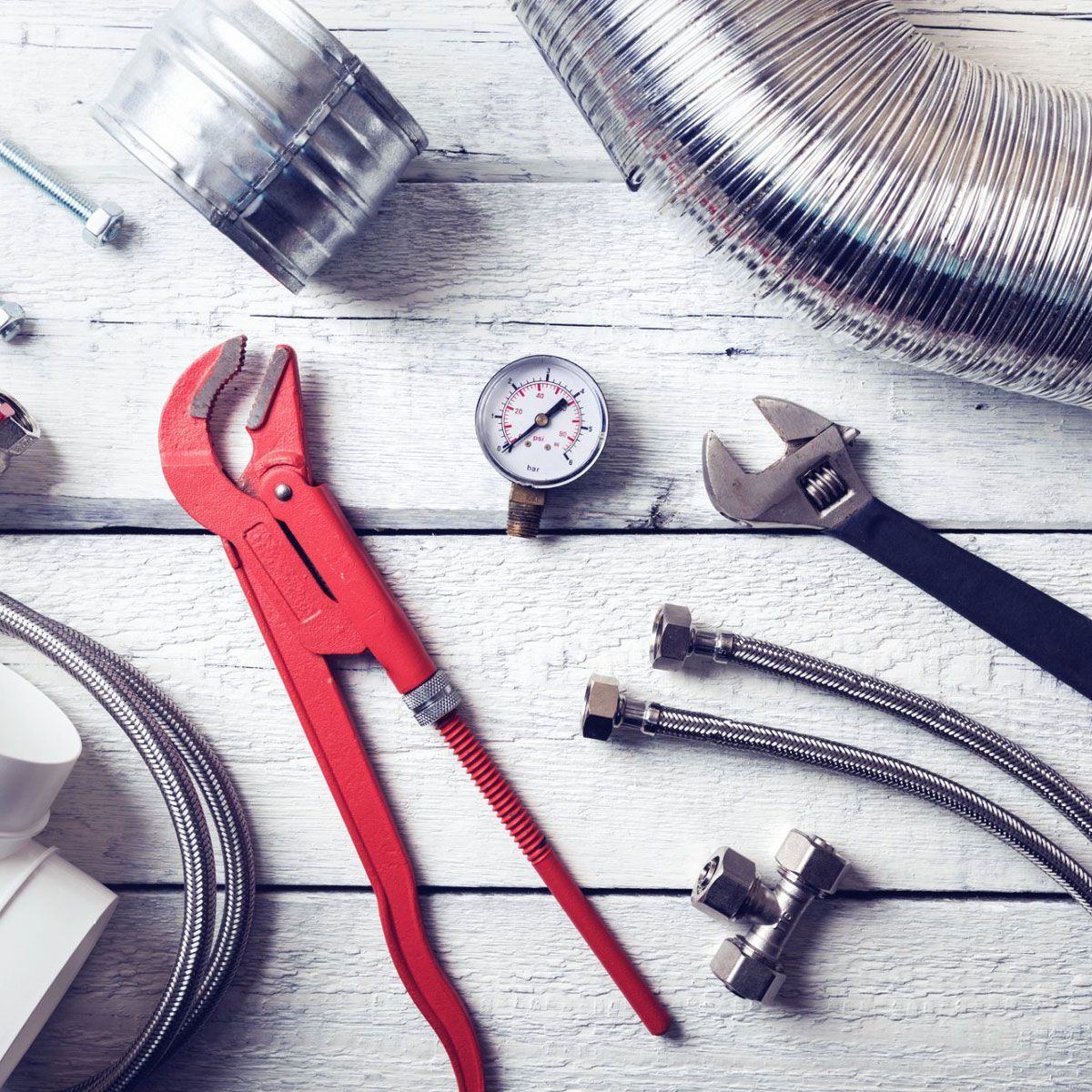 A bunch of plumbing tools are on a wooden table.