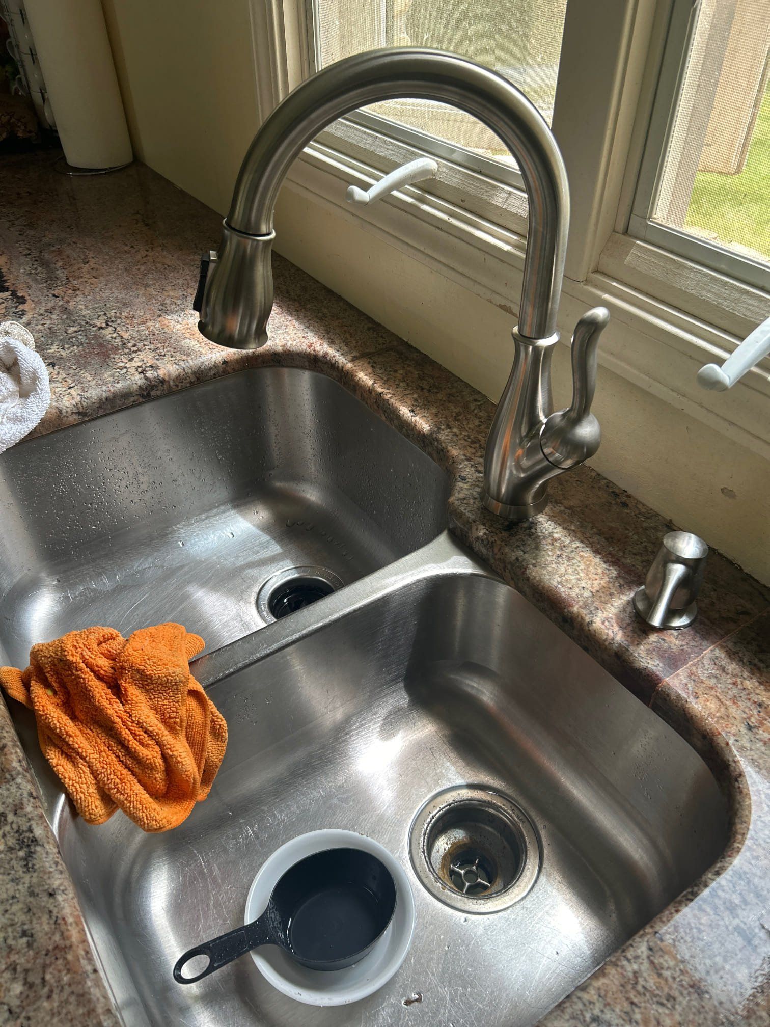 A kitchen sink with a faucet and a towel on the counter.