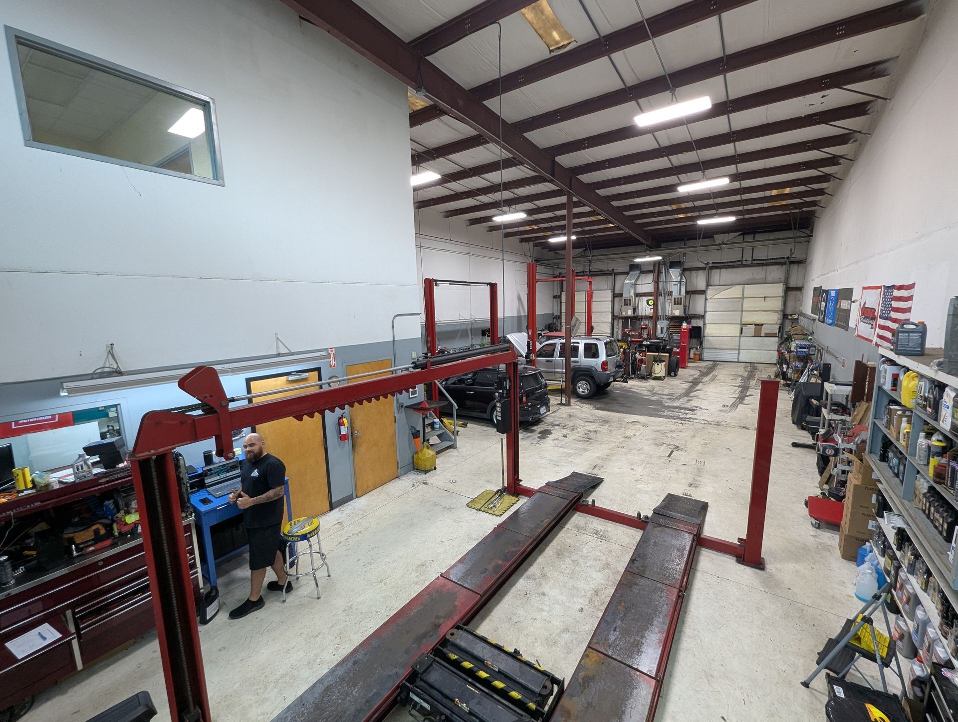 Garage interior with car lifts, tools, and a technician working | Vencam Auto Repair