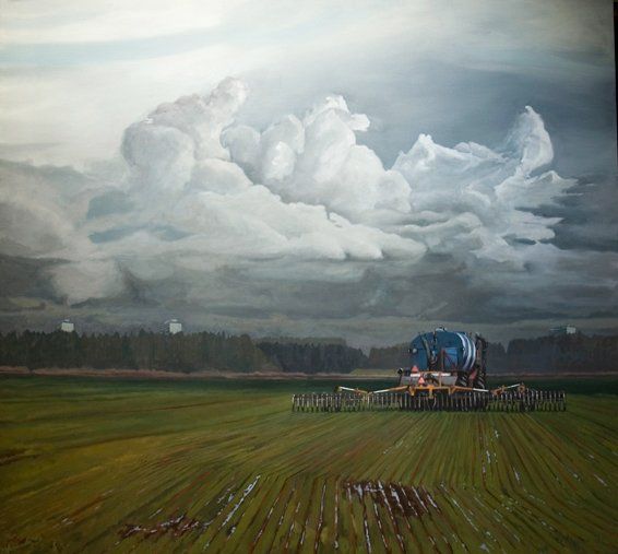 Een tractor met een grote tank rijdt over een groen, geploegd veld onder dramatische, opstuivende witte stormwolken.