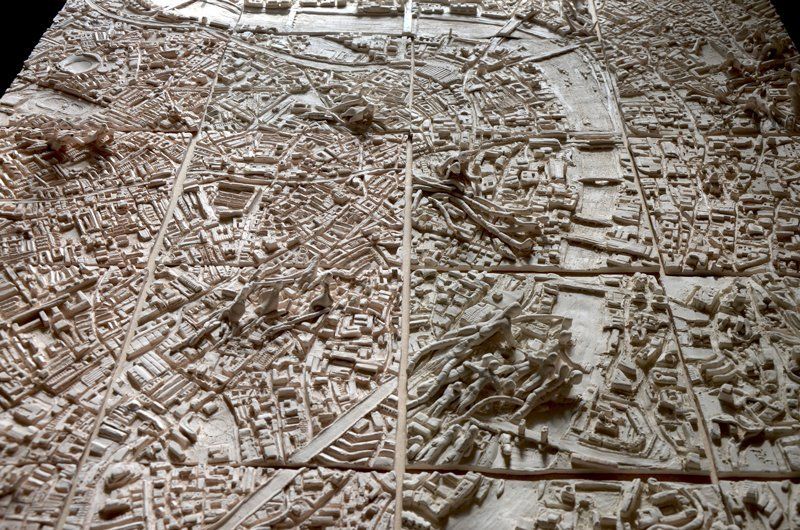 Een keramisch schaalmodel van een stadsplattegrond, met gebouwen en een centrale rivier.