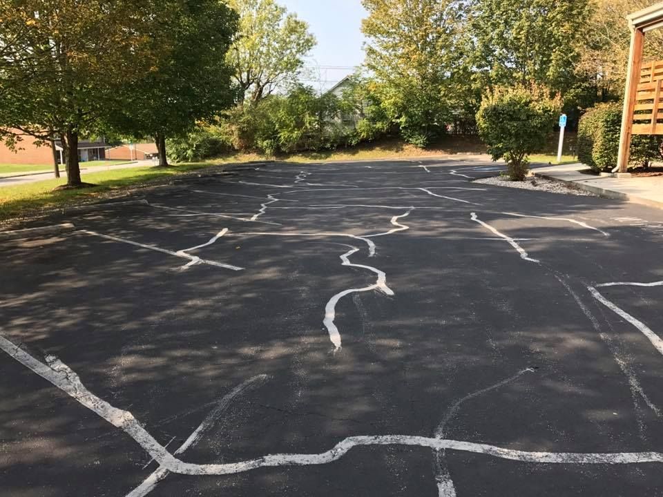 A parking lot with a lot of cracks in it and trees in the background.