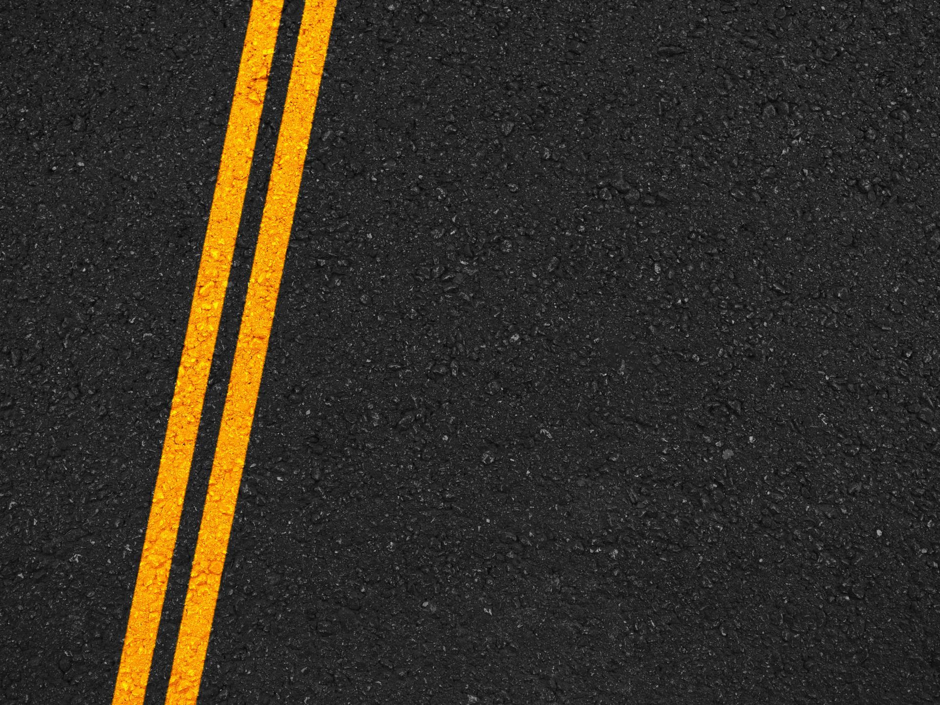 A close up of a road with two yellow lines on it. A close up of a road with two yellow lines on it.