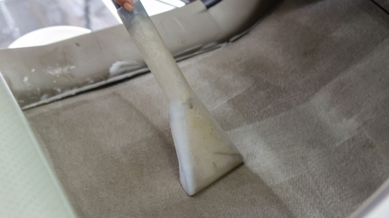 Close-up of a gray car seat with a seat belt strap across the cushion.