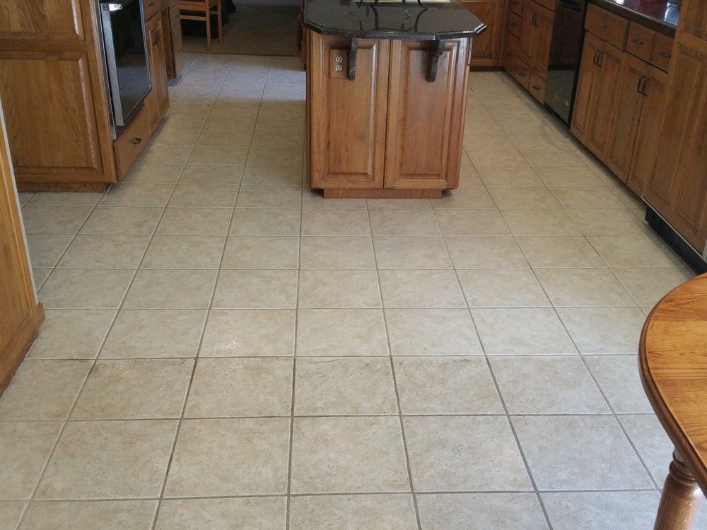 Kitchen with beige tile floor, wooden cabinets, and a central island with a dark countertop.