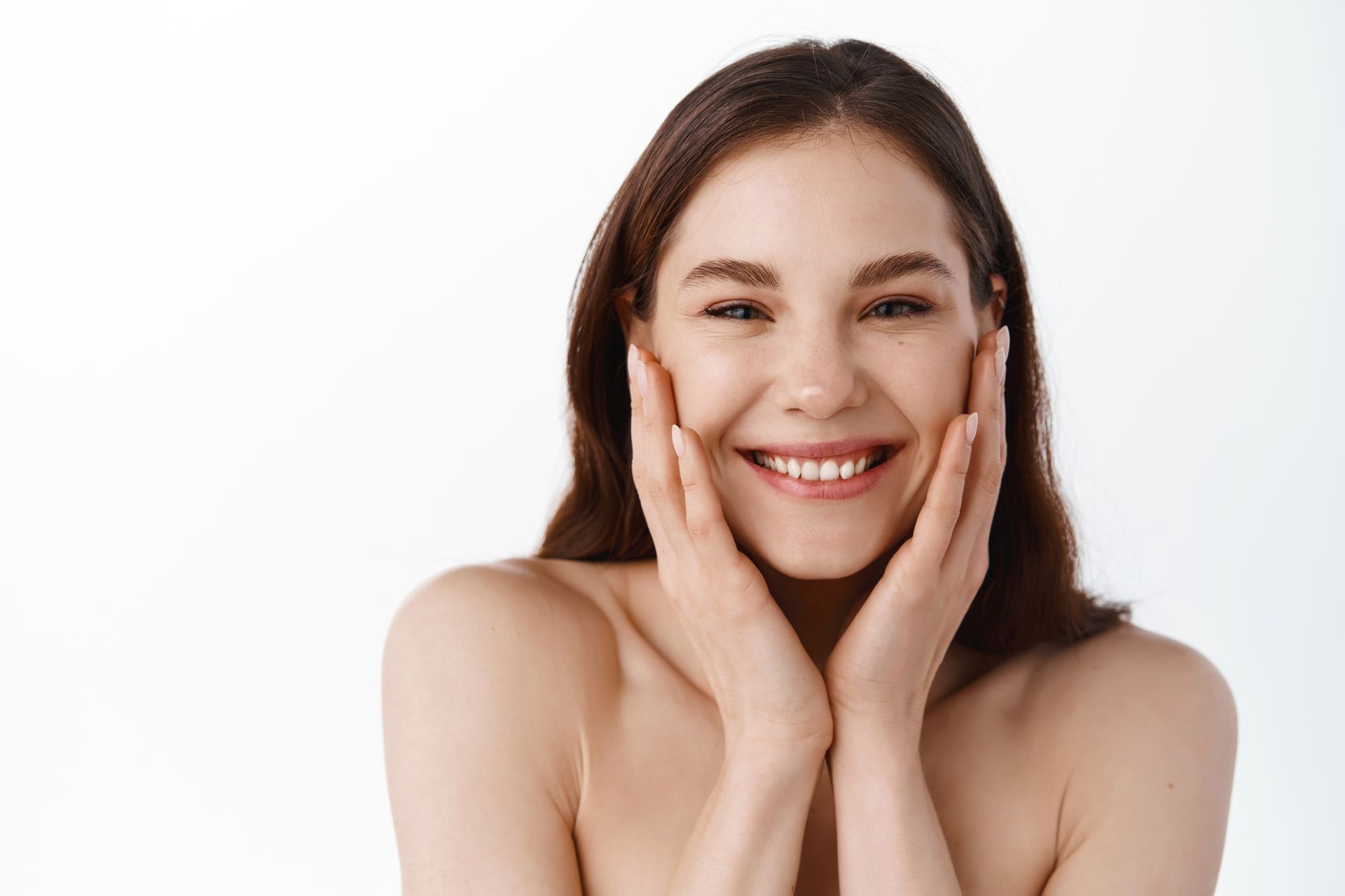 Smiling woman with hands on her cheeks against a white background