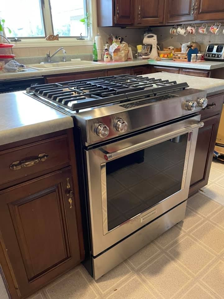Stainless steel range in a kitchen with dark cabinets and a light countertop.