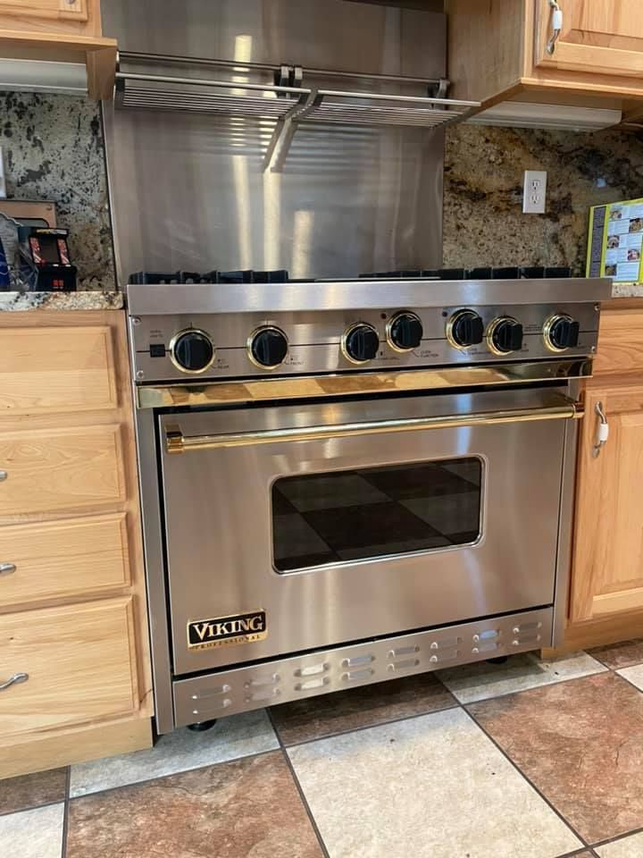 Stainless steel Viking range with six burners and a gold handle, in a kitchen setting.