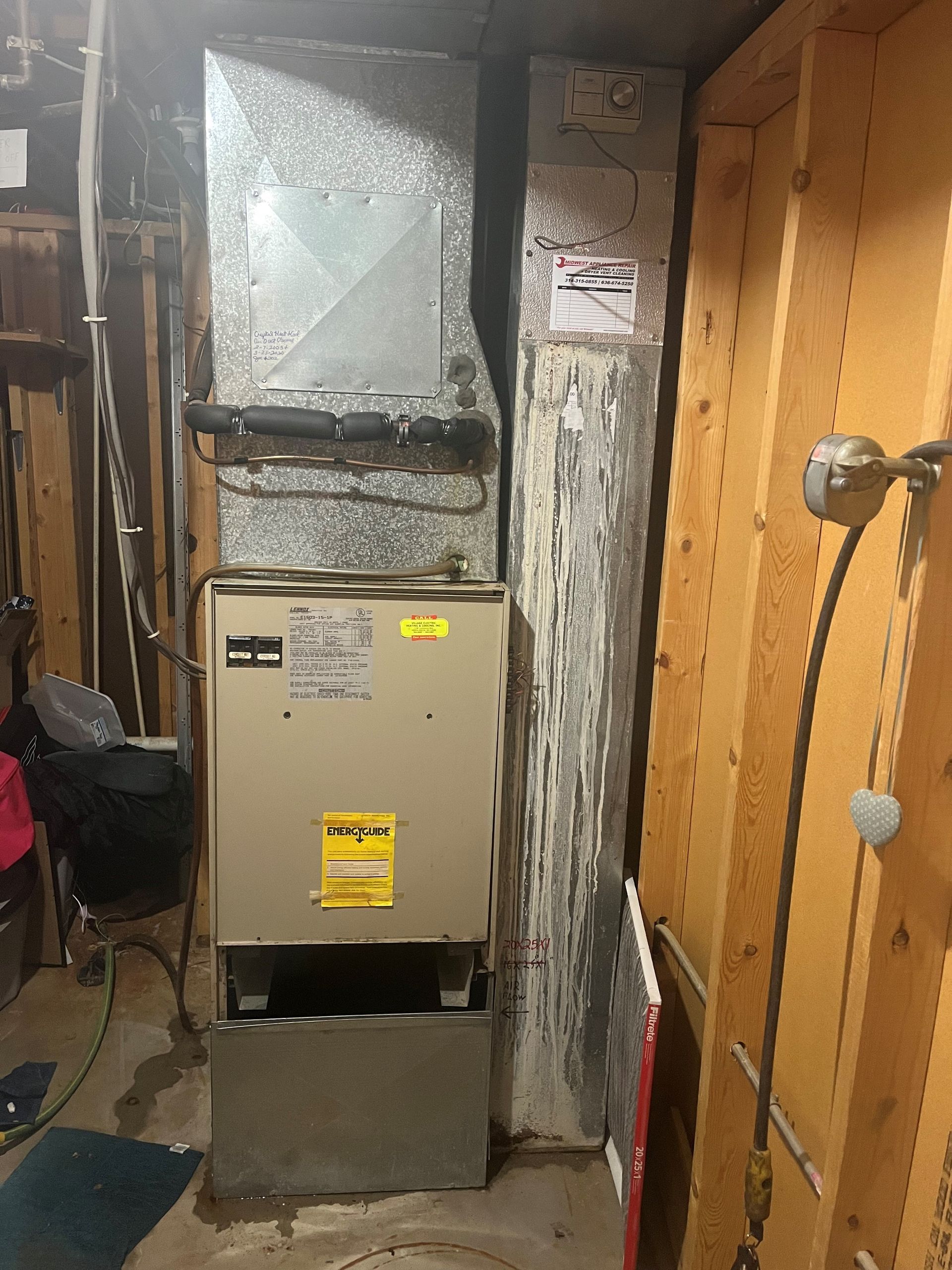 Furnace and ductwork against a wood-paneled wall in a basement.