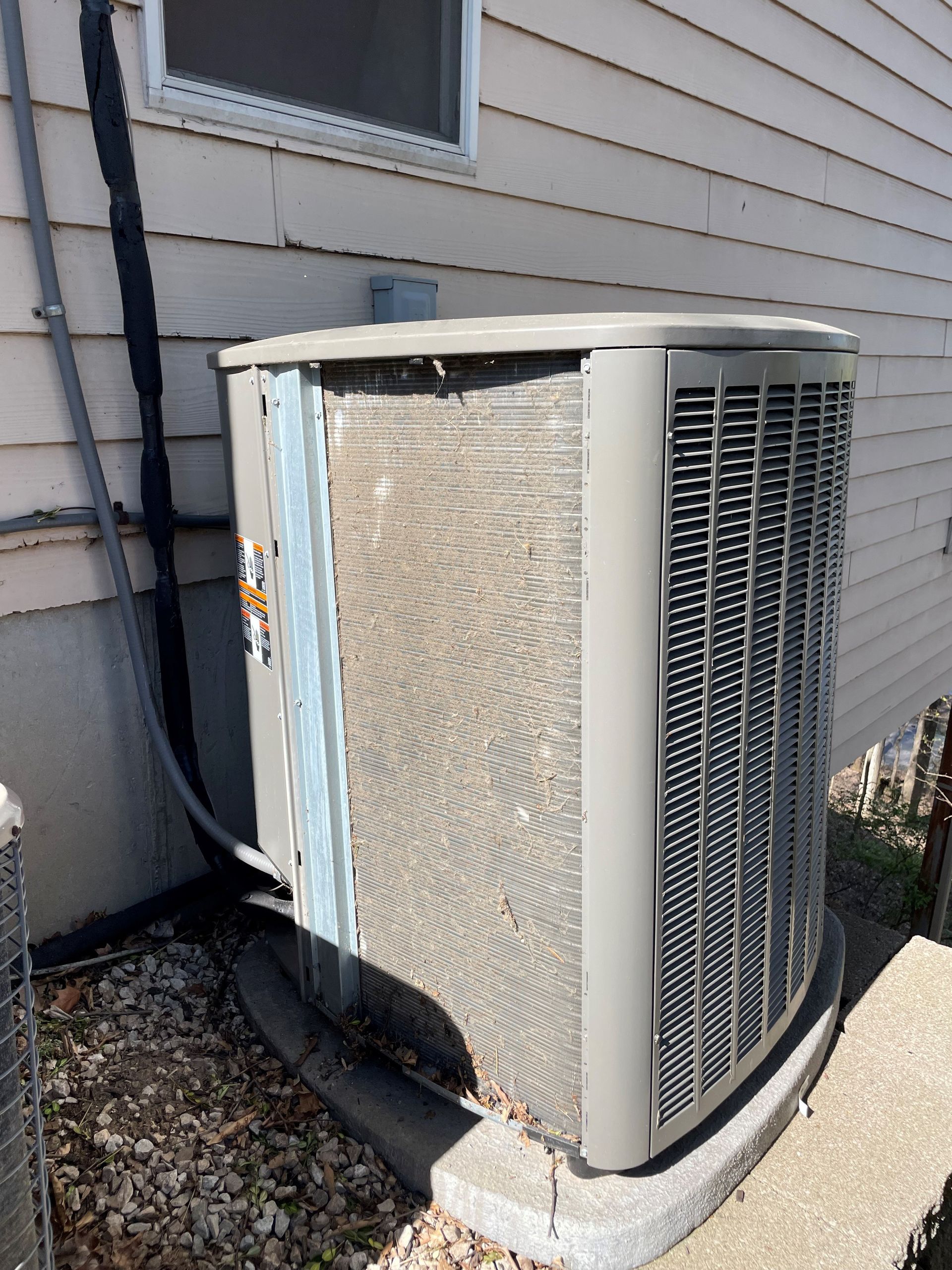 Damaged outdoor air conditioning unit near a building, showing a bent metal casing and exposed components.