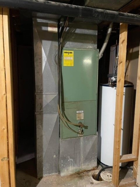 A furnace and water heater in a basement with ductwork.