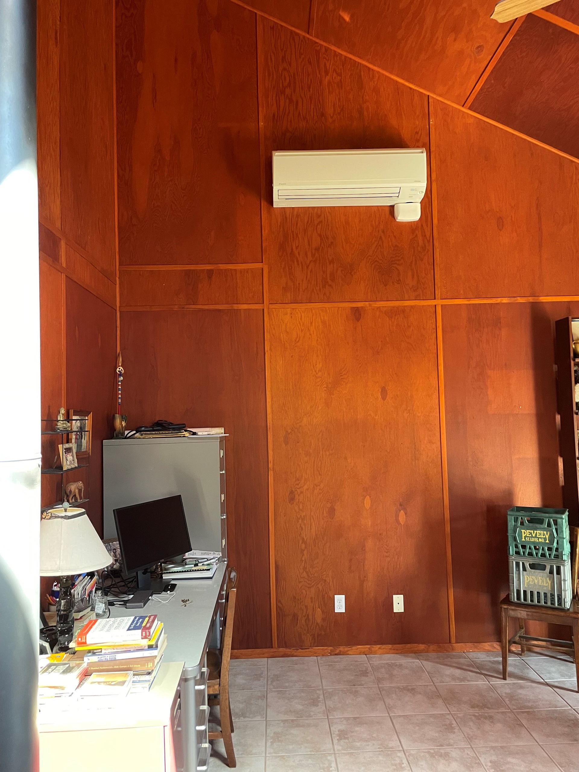 Orange-walled room with desk, computer, AC unit, and tiled floor.