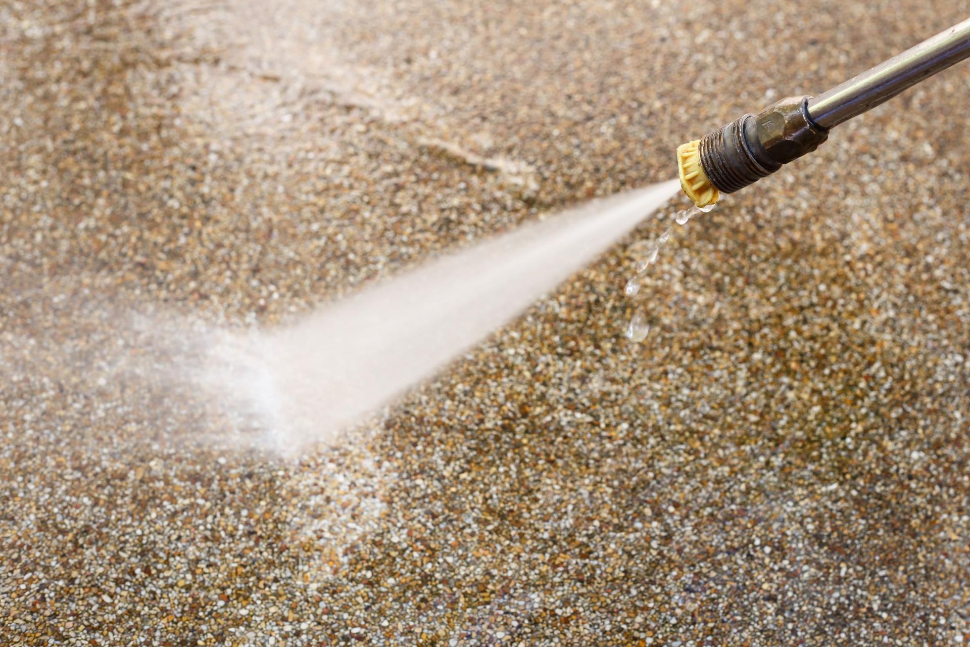 Pressure washer spraying water onto a concrete surface.