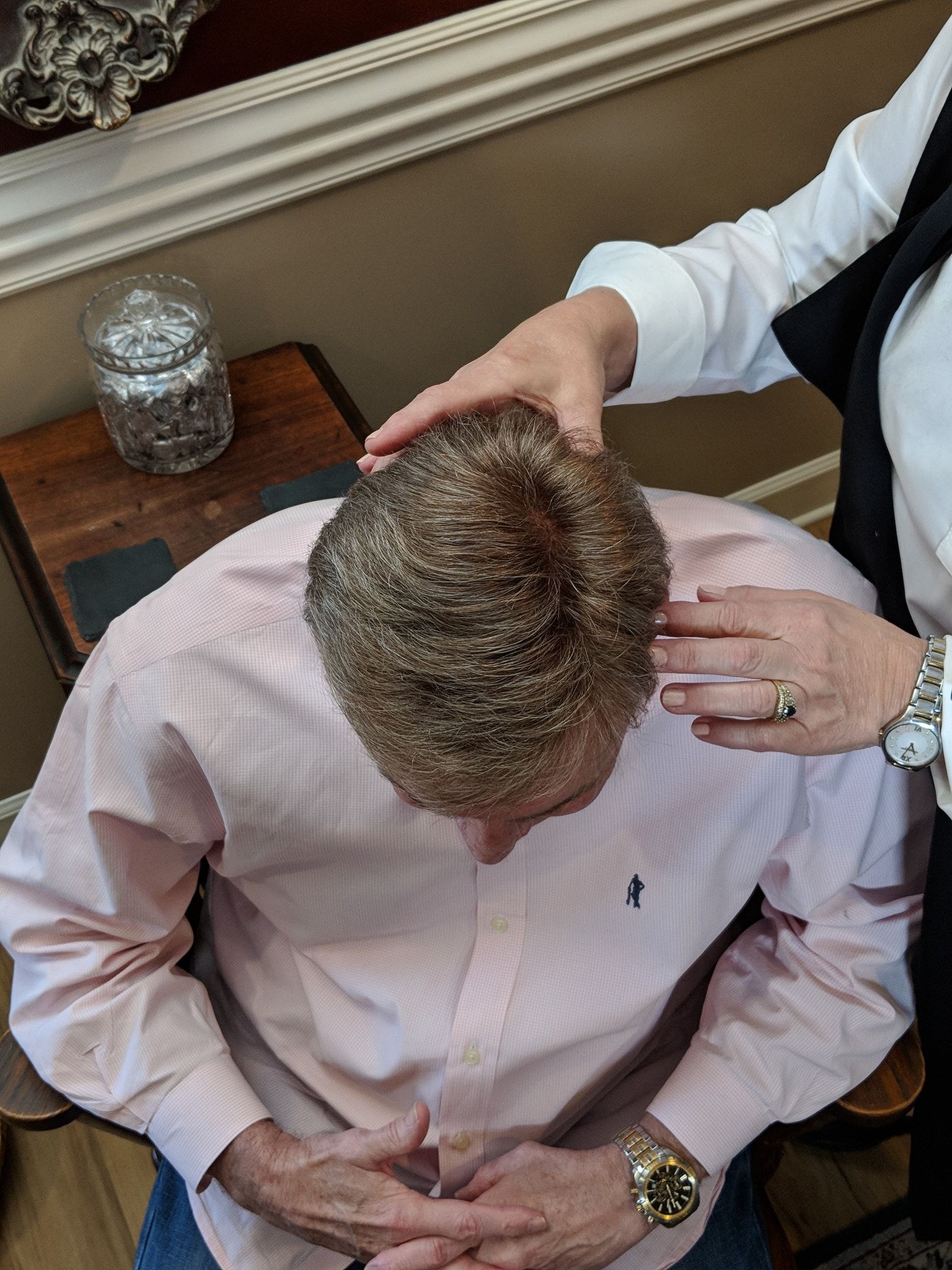 Person with hands on their head. Another person’s hands on their head. Man wearing pink shirt.