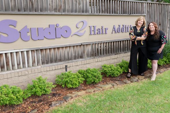 Two women stand near a sign for 