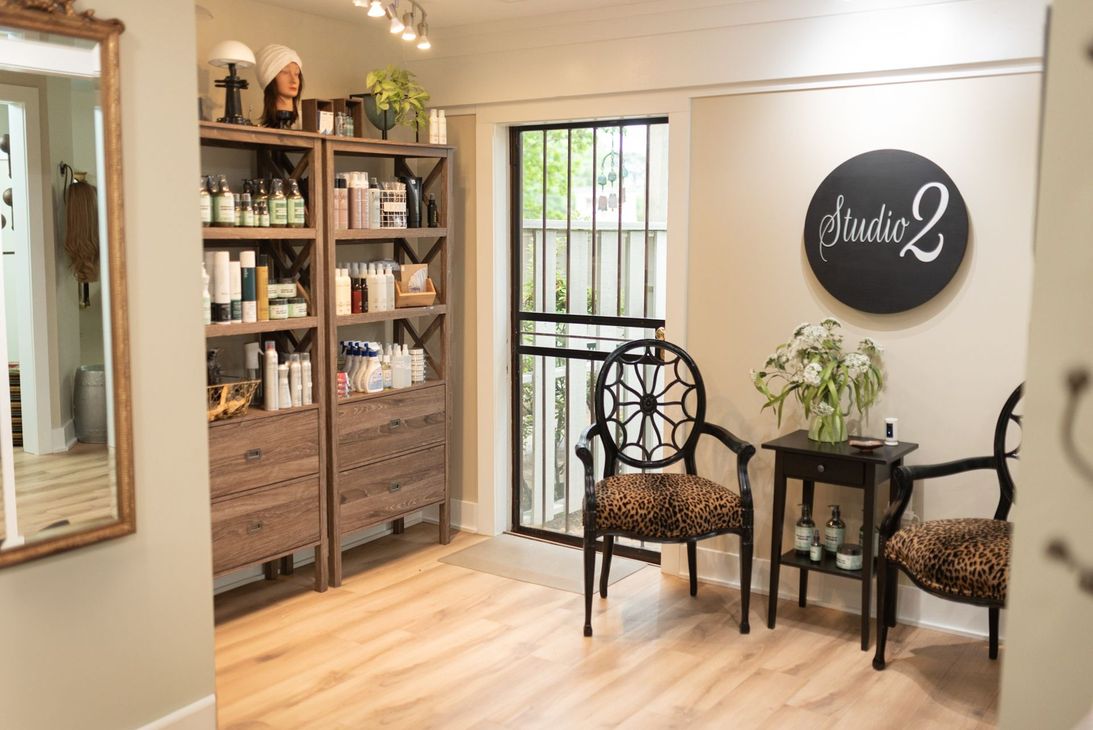 Waiting area of a salon with chairs, a small table, and a sign that says
