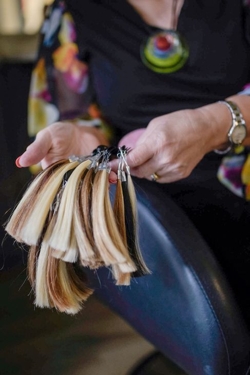 Person holding a swatch of hair extensions in varying shades of brown and blonde.