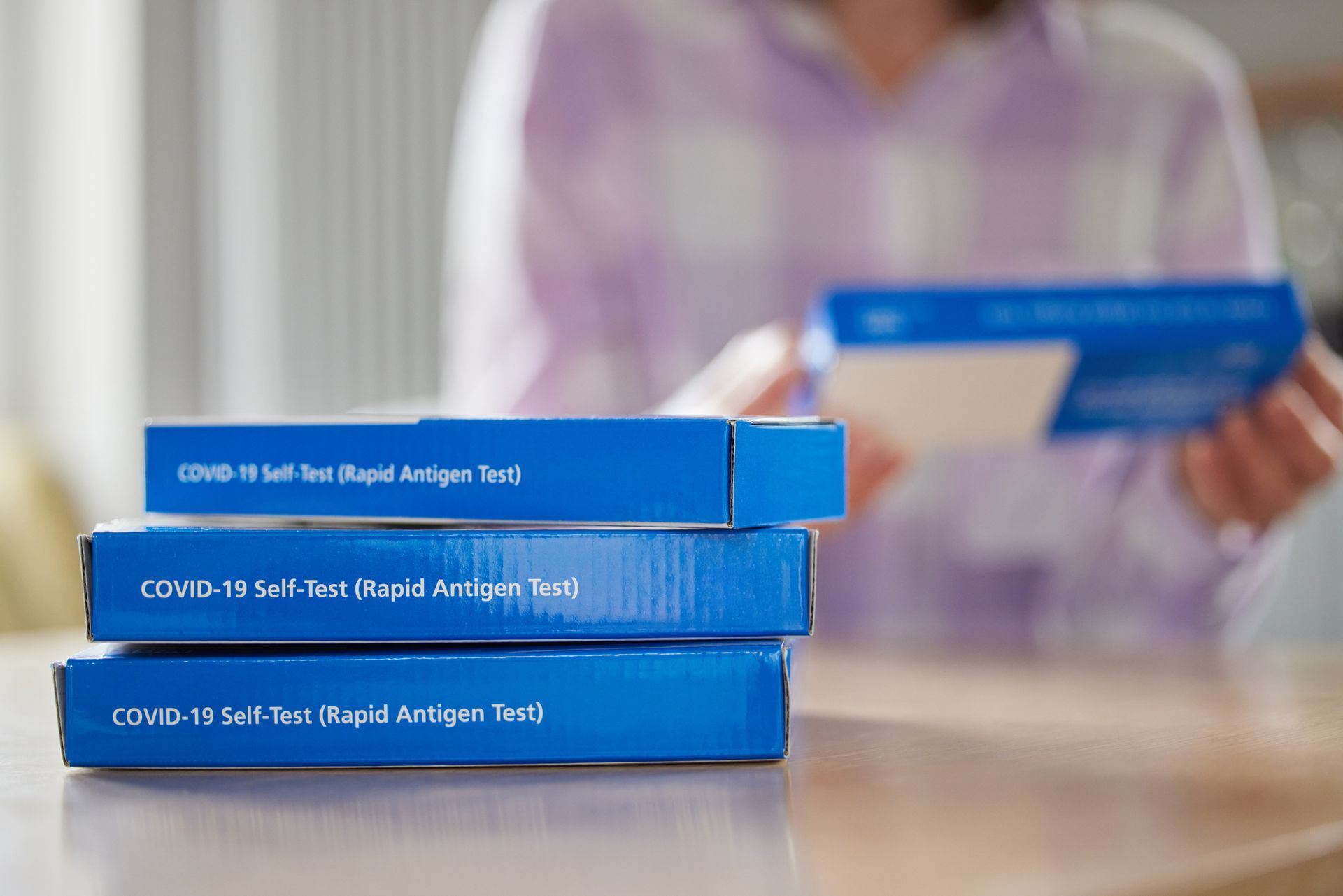 A person is sitting at a table with a stack of blue boxes.