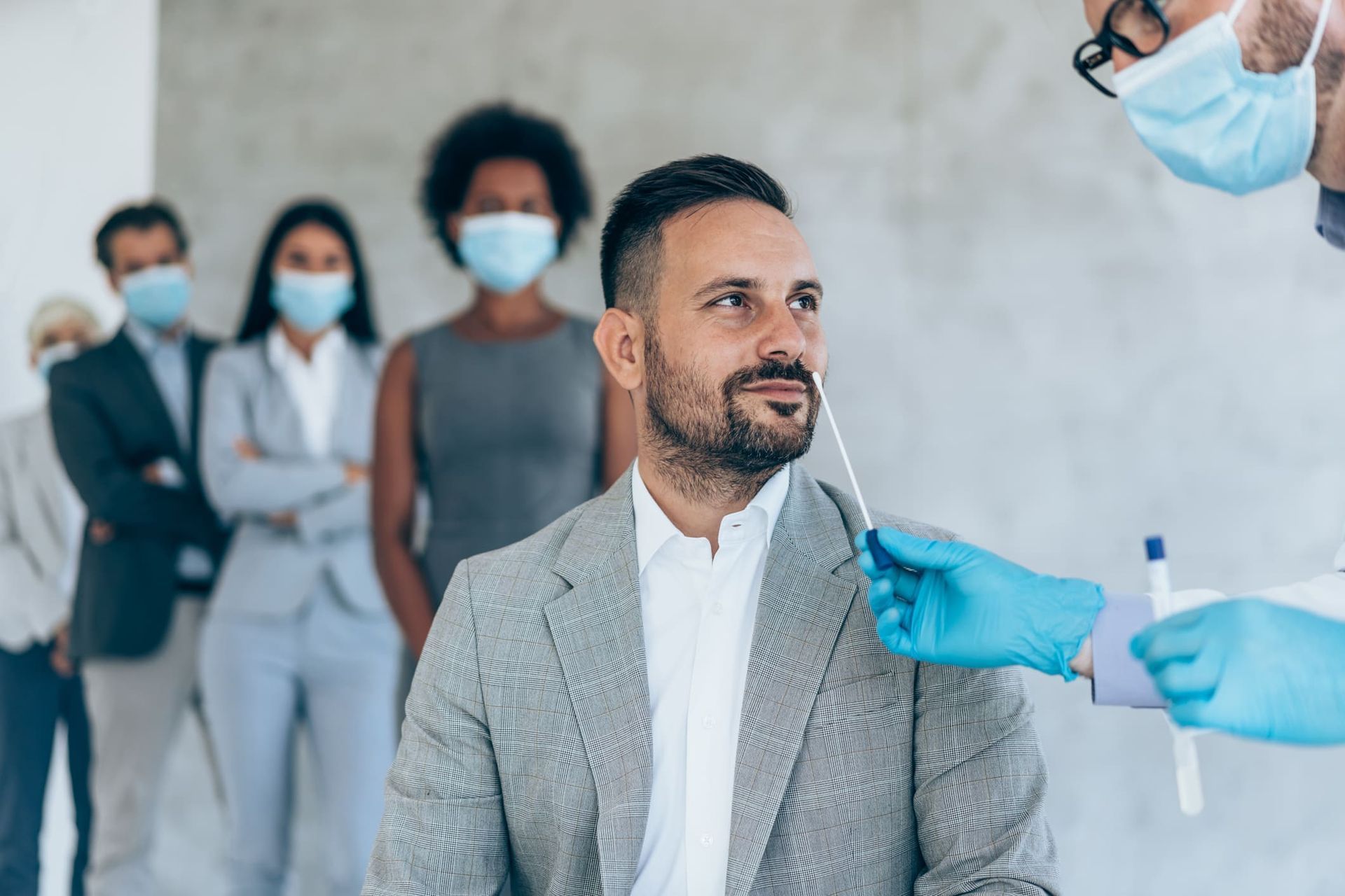 A man in a suit is getting a swab test from a doctor.