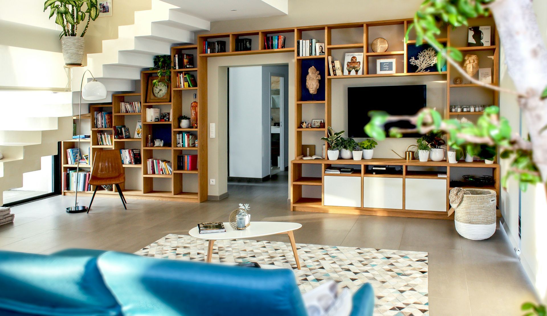 Bright modern living room with wooden shelves, indoor plants, and a blue sofa