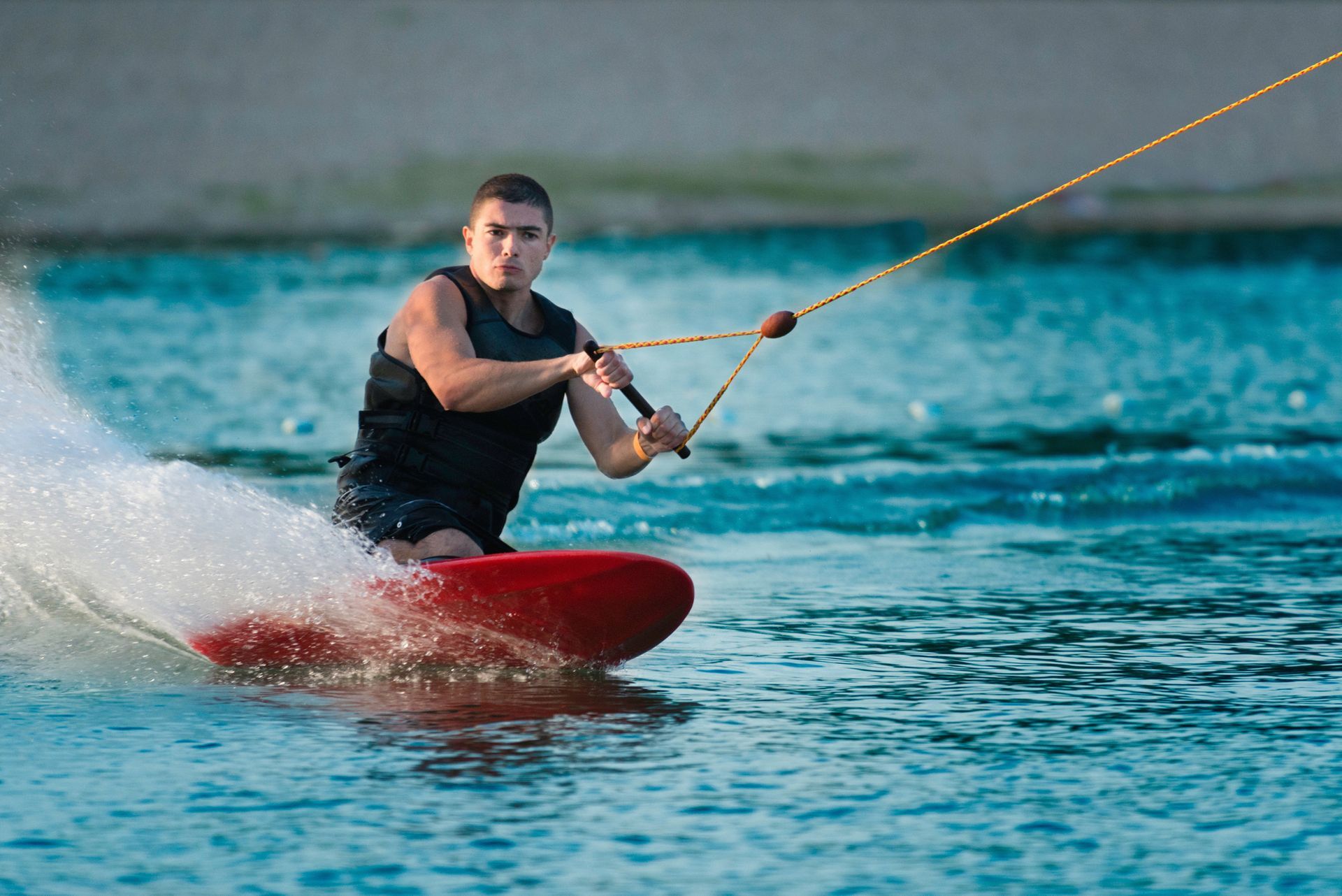 Un hombre está practicando esquí acuático sobre una tabla roja en el agua.