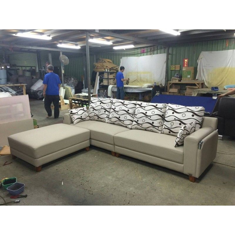 A man in a blue shirt is standing next to a couch in a room