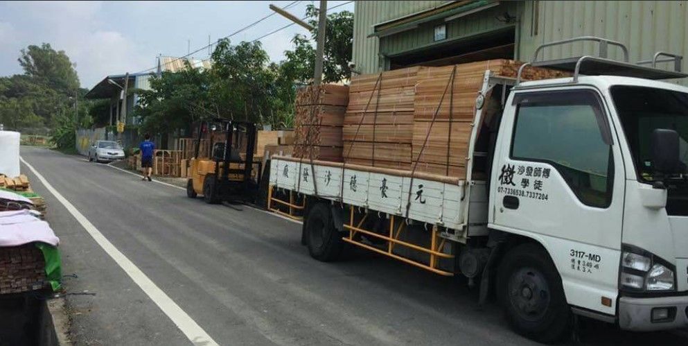 A white truck is parked on the side of the road next to a forklift.